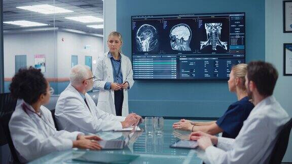 医院会议室:女神经科医生在电视屏幕上展示MRI扫描脑图像神经科学家团队医生讨论病人治疗药物研究医学发展