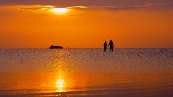 日落时分在海上散步的夫妇