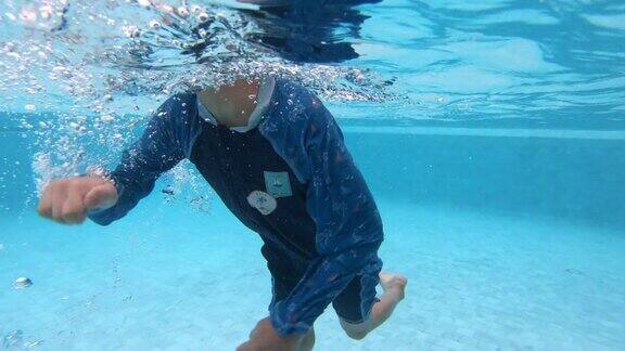 一个男孩享受暑假快乐的孩子潜入游泳池的水下视图4K慢动作场景
