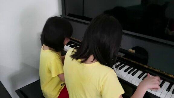 两个亚洲华人女孩一起在家里弹钢琴玩