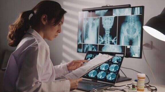 一位亚洲女医生正在看并分析她电脑上的x光影像扫描图