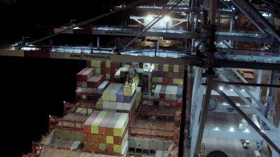 夜间装卸集装箱时装载集装箱的货轮站在港口泊位上的鸟瞰图