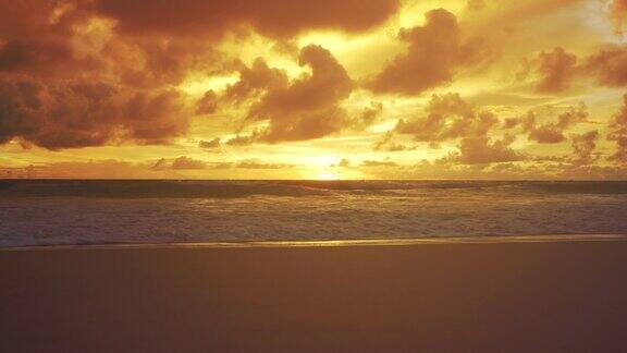 广角拍摄橙色和金色日落多云的天空海浪海滩