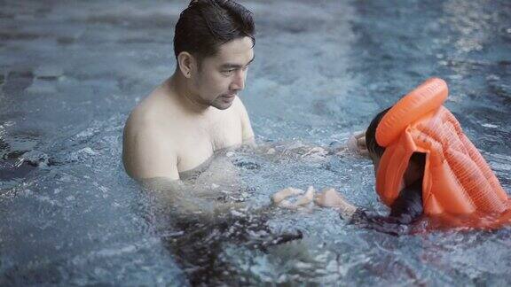 父亲在游泳池里教儿子游泳
