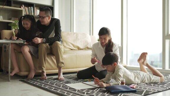 一个年轻的亚洲华人家庭周末在家里的客厅公寓里做作业和画画