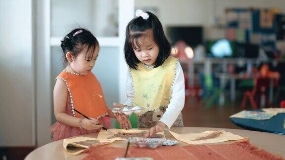 2名亚洲华人蒙氏学龄前女孩喜欢在教室里画画