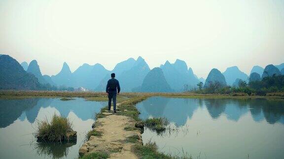 中国桂林一名背着背包的男游客走在稻田上