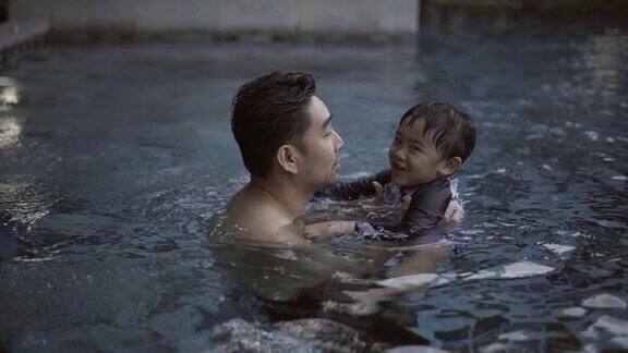 爸爸和儿子在游泳池里玩