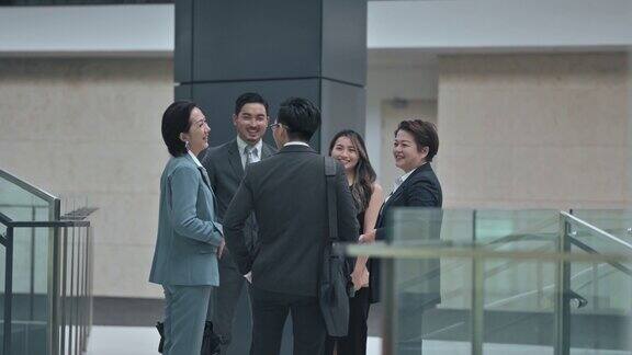 下班后亚洲华人穿着工作服在办公楼走廊上交谈