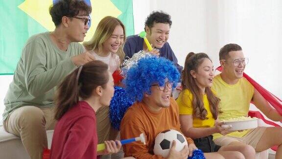一群亚洲男女朋友一起在家看电视上的体育比赛