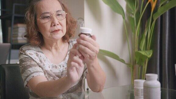 资深亚洲妇女阅读药物说明说明老妇人拿着药片瓶子上的标签并阅读
