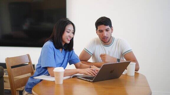 年轻的成年亚洲女护士学生穿着磨砂服坐着用笔记本电脑学习在大学校园的会议室里在线学习