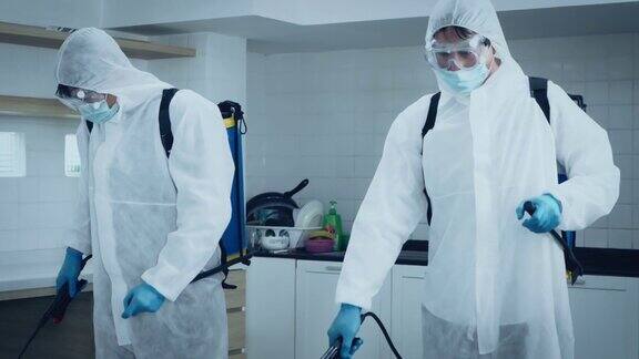 2名专家男性身着防护服戴口罩在办公室和病原体滋生地喷洒消毒4K分辨率COVID-19效应慢动作