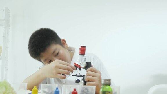 亚洲男生穿着实验服在科学课上使用显微镜教育理念