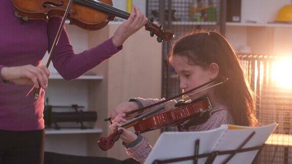 一个年轻女子在教一个小女孩拉小提琴