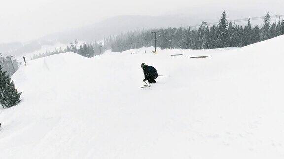 一个滑雪者在完整的冬季装备完成一个“开关Rodeo540”技巧在一个跳跃与森林和滑雪缆车在背景在科罗拉多州博尔德附近的埃尔多拉滑雪度假村在一个下雪的阴天