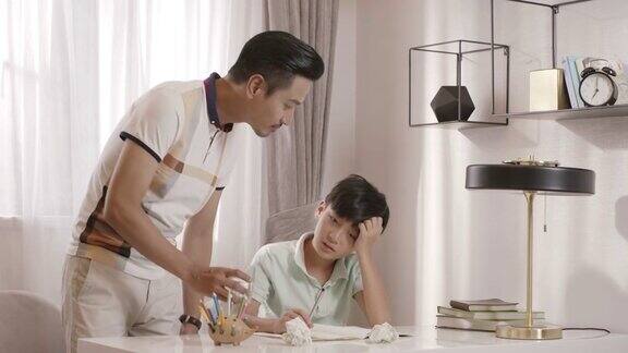 一位亚洲父亲走进阅览室和儿子聊天儿子正在做作业