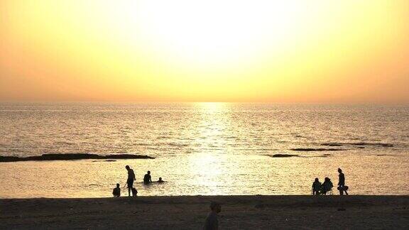 日落时海滩上的人们
