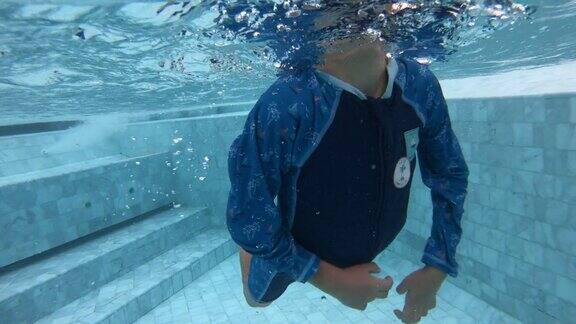 一个男孩享受暑假快乐的孩子潜入游泳池的水下视图4K慢动作场景