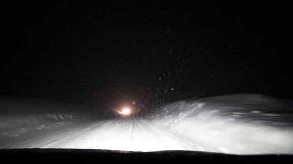 一辆汽车在夜间高速公路上穿过暴风雪的挡风玻璃