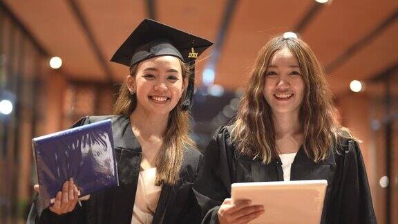 亚洲十几岁的女孩穿着毕业礼服布带着心情开心穿黑色毕业礼服的人持有毕业证书