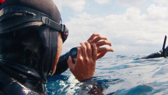 自由潜水者从平台上漂到大海深处将手表放在台前