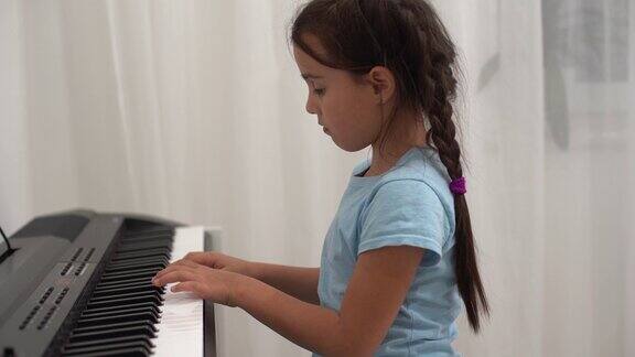 小女孩对着钢琴键盘微笑