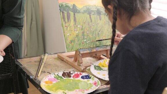 在美术教室里一个小女孩正专注地在画布上画亚克力彩画