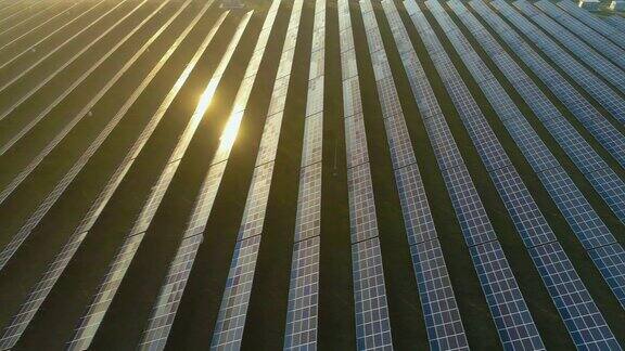 大面积的蓝色光伏太阳能电池板在日落阳光反射鸟瞰图向右偏飞远景