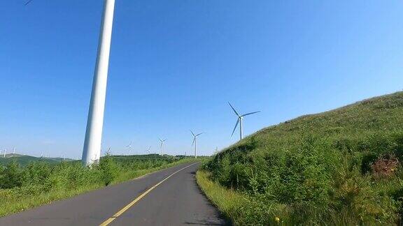 4K实时拍摄中国沿着松林公路行驶穿过风力涡轮机