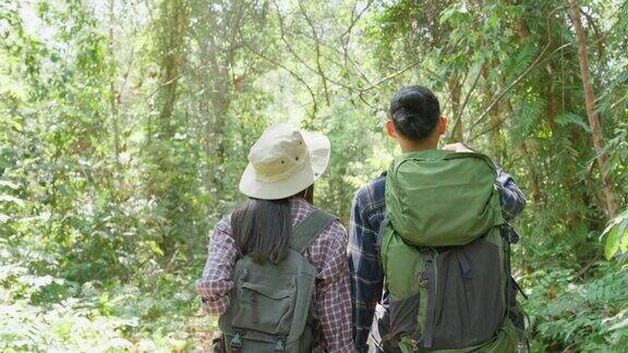亚洲男人和女人背包客朋友一起在森林里旅行迷人的年轻夫妇在夏天的假期旅行中散步和探索自然木材的幸福和乐趣