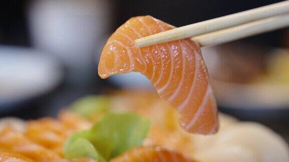 用筷子夹起三文鱼刺身的特写镜头