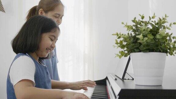 亚洲女孩和她的母亲弹钢琴的慢镜头缩小