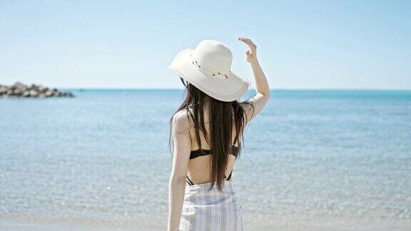 年轻的中国女游客在海边穿着泳装和夏帽