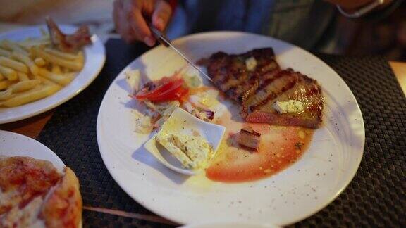 盘子里的牛排特写在餐厅用餐的人切牛肉用餐