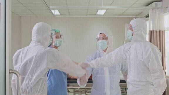 一群穿着防护服在医院急诊室工作的医生在成功救治新冠肺炎患者后高兴地拍拍手