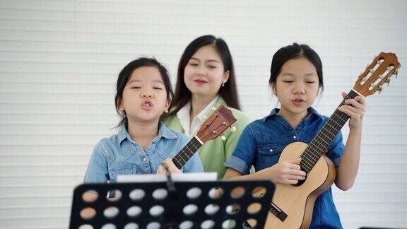 在一所音乐学校一位美丽的亚洲老师正在教学生演奏音乐和唱歌教育孩子的发展