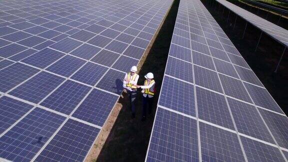 技术工程师在阳光下观察太阳能电池在太阳能发电厂检查太阳能电池板