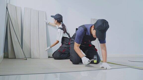 亚洲有魅力的工匠或木匠在地板上安装层压板来翻新公寓或房子木匠妇女检查和清点拼花地板帮助建筑工人修理家里的走廊