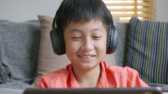 肖像亚洲学生男孩在家里使用平板电脑