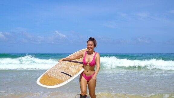 4K亚洲妇女抱着冲浪板从海洋在夏日阳光灿烂的一天