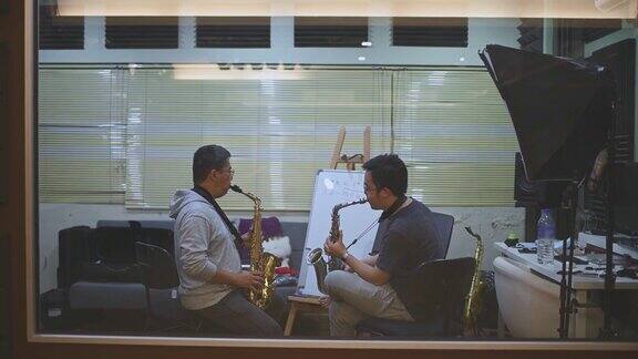亚洲华人中年男子在音乐工作室向他的导师学习萨克斯乐器