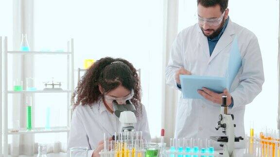 科学家小组在实验室里使用显微镜生物技术研究员科学家在医学发展实验室为疫苗开发看显微镜