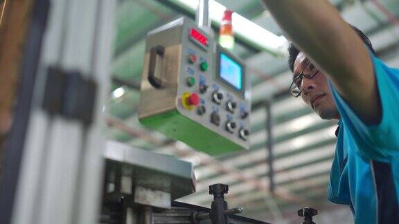 亚洲华人男性生产线工人操作贴标机在装瓶厂矿泉水饮用水厂