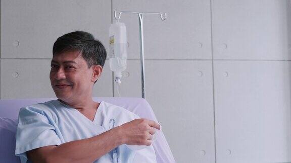 一名老年男性患者摘下口罩坐在患者床上一名亚洲男子因感染COVID-19住院