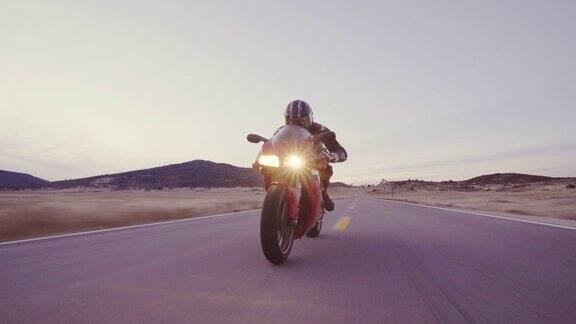 夕阳西下一个骑摩托车的人沿着笔直的乡村公路高速行驶