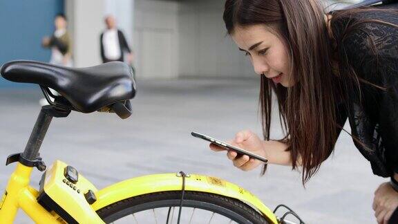 一名女子在城市用智能手机扫描共享自行车的二维码