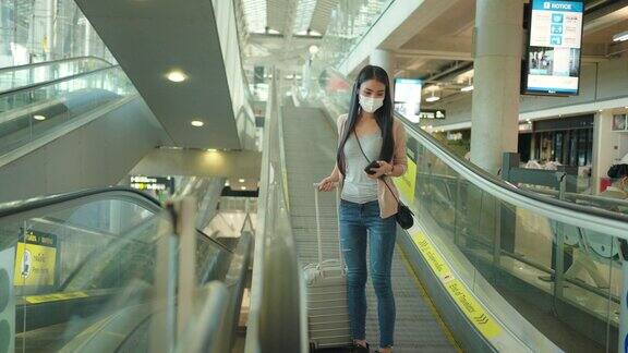 亚洲妇女在机场使用手机戴医用口罩