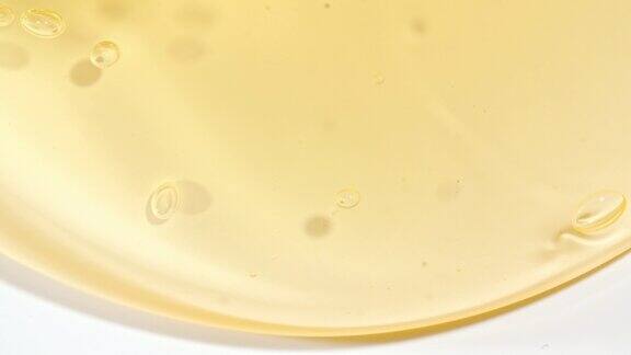 透明黄色化妆液凝胶泡沫在白色表面流动的乳霜的微距镜头天然有机化妆品医药
