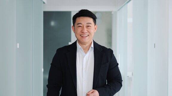 英俊的微笑的亚洲商务男子在正式穿着看着相机在办公室走廊东亚男性商人从事金融、营销、法律银行项目一个成功人士的肖像